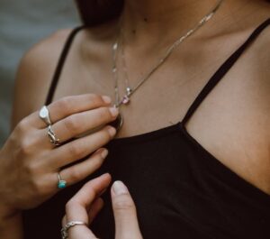 Quels bijoux pour une femme de 40 ans ? Femme en tenue noire avec des bagues et un pendentif