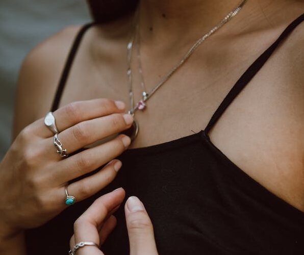 Quels bijoux pour une femme de 40 ans ? Femme en tenue noire avec des bagues et un pendentif
